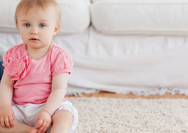 Underbar blond bebis tittar på kameran när du sitter på en carpe — Stockfoto