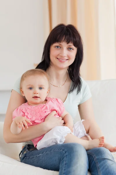 Mulher encantadora segurando seu bebê em seus braços enquanto sentado em um s — Fotografia de Stock