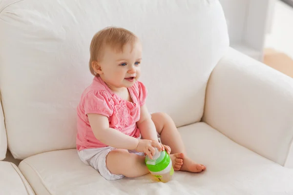 Blondes Baby spielt auf dem Sofa mit einem Ball — Stockfoto