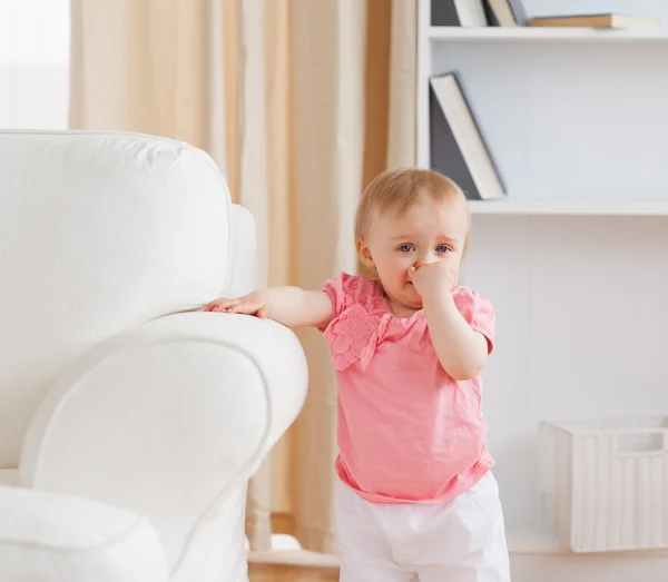 Baby steht neben einem Sofa — Stockfoto