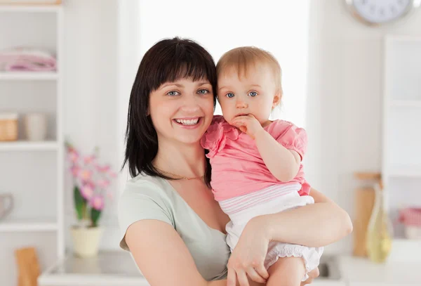 Beautiful woman holding her baby in her arms while standing — Stock Photo, Image