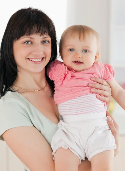 Good loooking woman holding her baby in her arms while standing — Stock Photo, Image