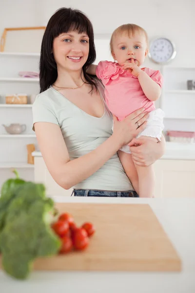 Pretty woman holding her baby in her arms while standing — Stock Photo, Image
