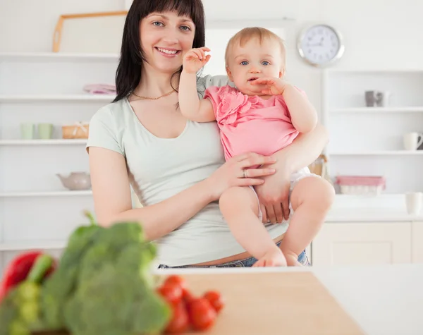 Lovely woman holding her baby in her arms while standing — Stock Photo, Image