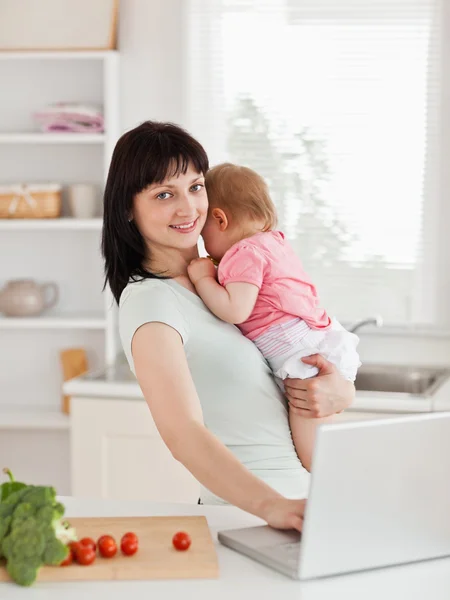 Good looking brunette woman holding her baby in her arms — Stock Photo, Image