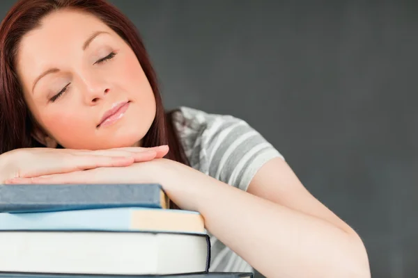 Junge Studentin schläft auf ihren Büchern Stockbild