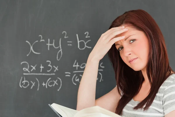 Tankeväckande kvinna försöker lösa en ekvation Stockbild