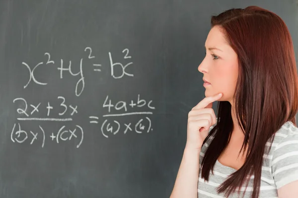 Nachdenkliche süße Frau versucht, eine Gleichung zu lösen Stockbild
