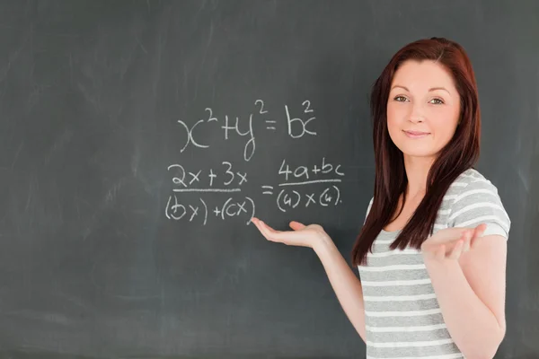 Lächelnde junge Frau beim Lösen einer Gleichung Stockbild