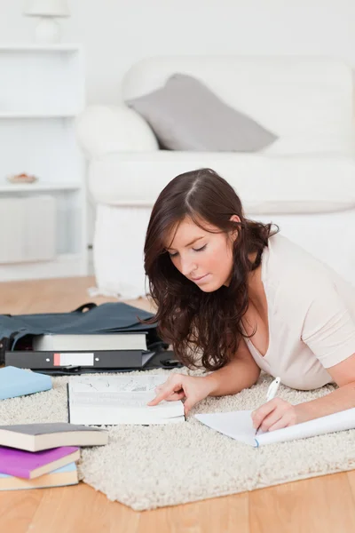 Young beautiful female writing on a notebook while lying on a ca Stock Image