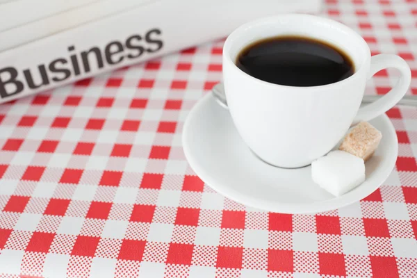 Una tazza di caffè e un giornale su una tovaglia — Foto Stock