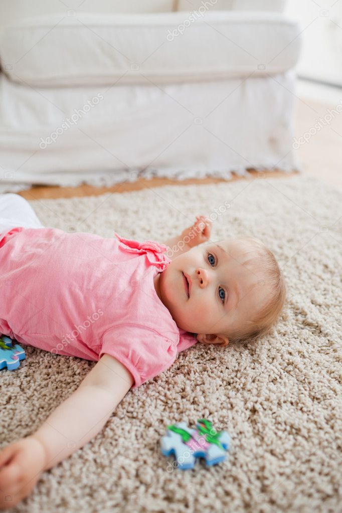 Un bebé está acostado sobre una alfombra en una habitación con un
