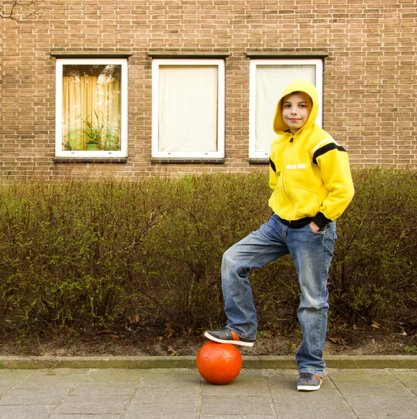 Sevimli genç çocuk içinde turuncu topu ile sarı hoodie Stok Resim