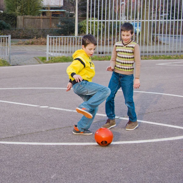 Dos chicos pateando fútbol en el patio de recreo deportivo —  Fotos de Stock