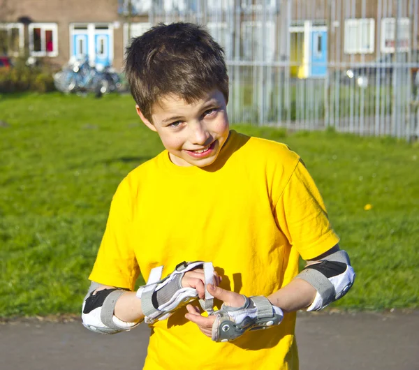 Garoto adolescente sorridente em kit de proteção de patins — Fotografia de Stock