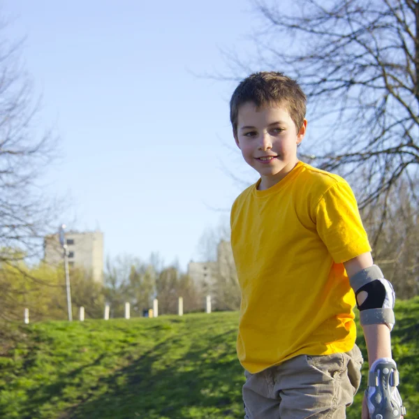 Ragazzo sorridente adolescente in roller-blading protezione kit in un pattino — Foto Stock