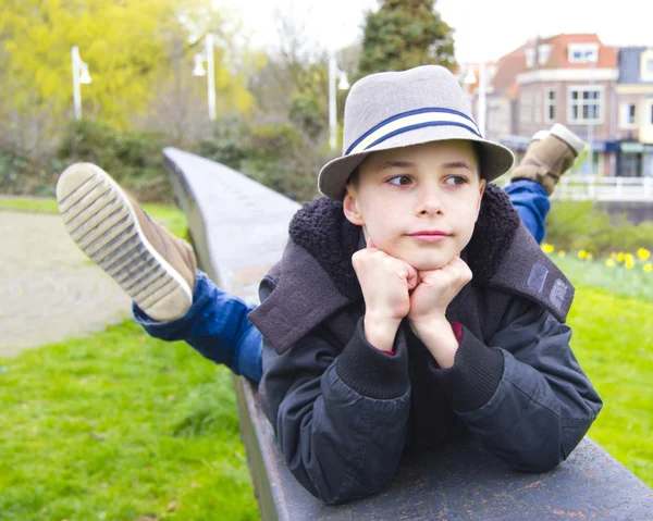 Komik genç çocuk parkı parapetin üzerinde yalan — Stok fotoğraf