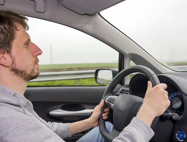 stock image A man driving a car in the rain