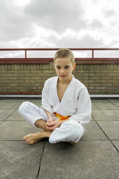 Judoka teen pojke sitter på taket (himmel bakgrund) — Stockfoto