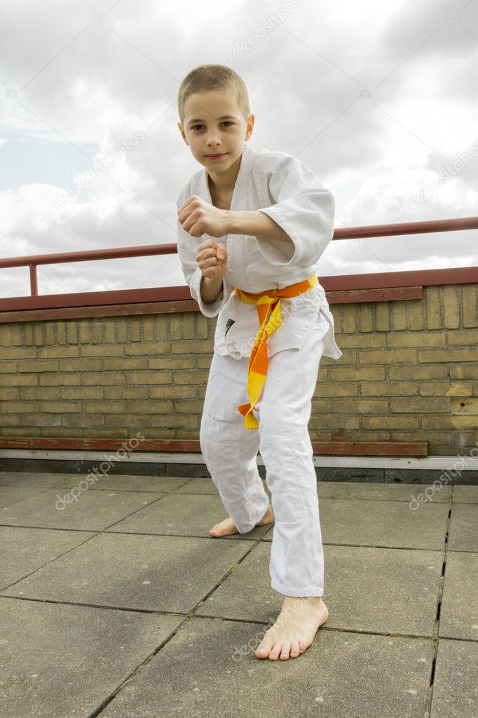 Judoka teen boy training judo on the sky background