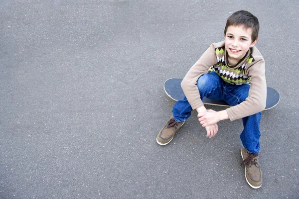 Teenage boy sitting on the skateboard — Stok fotoğraf