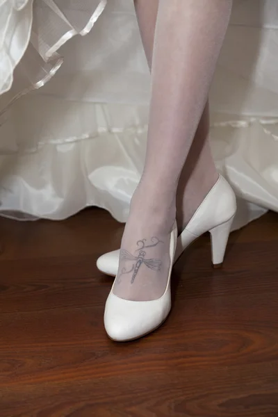 Menyasszonya mutatja a tetoválás sárkány-fly és a fehér cipő Jogdíjmentes Stock Képek