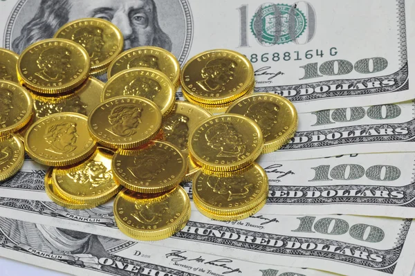Goldmünzen und 100-Dollar-Scheine lizenzfreie Stockbilder