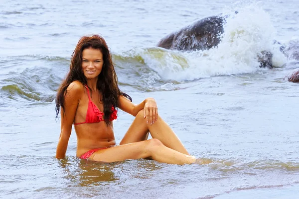 Deniz sahilinde oturan kırmızı bikinili seksi kadın — Stok fotoğraf
