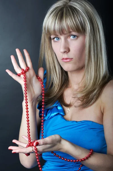 Vrouw in blauwe jurk met kralen in haar hand — Stockfoto