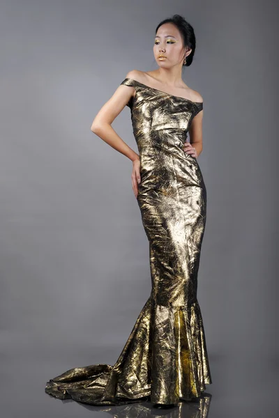 Красивая азиатка в золотом вечернем платье — стоковое фото