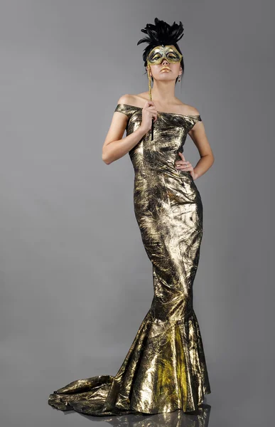 Женщина в красивом золотом платье с маской — стоковое фото