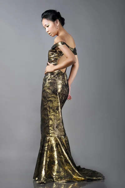 Όμορφη γυναίκα της Ασίας σε χρυσό φόρεμα βράδυ — Φωτογραφία Αρχείου