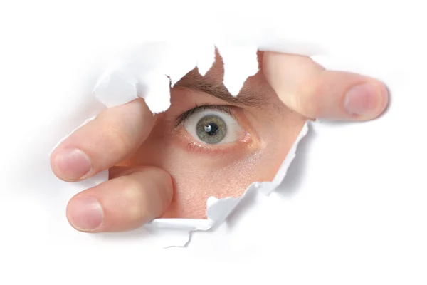 Eye looking through a hole in paper — Stock Photo, Image