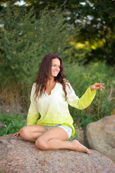Smiling woman sit on the stones — Stock Photo, Image