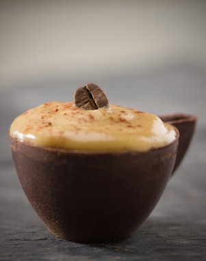 Shallow coffee mousse in a dark chocolate cup clipart