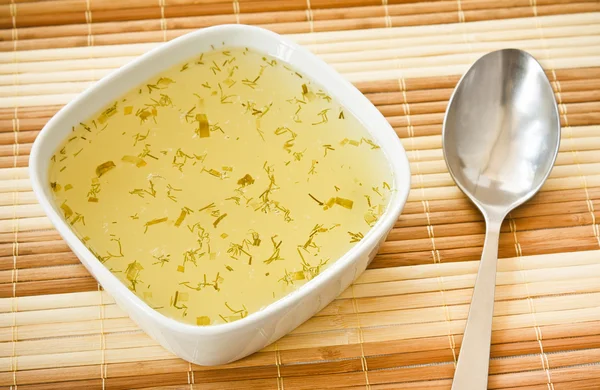 竹マットの上の鶏スープと金属スプーンのホット皿 — ストック写真