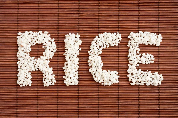 The word "Rice" from rice on a Dark Bamboo Mat background — Stock Photo, Image