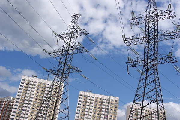 stock image Transmission line against the blue sky with clouds and modern apartment houses