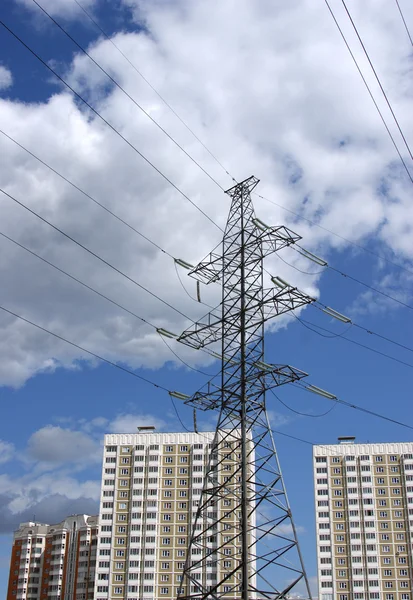 stock image Transmission line against the blue sky with clouds and modern apartment houses