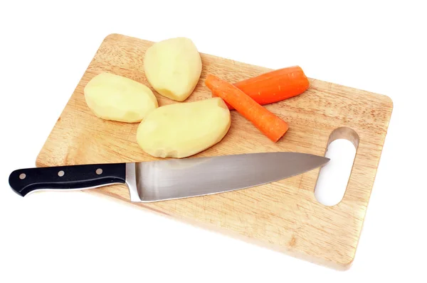 Cuchillo, papa y zanahorias en una tabla de madera —  Fotos de Stock