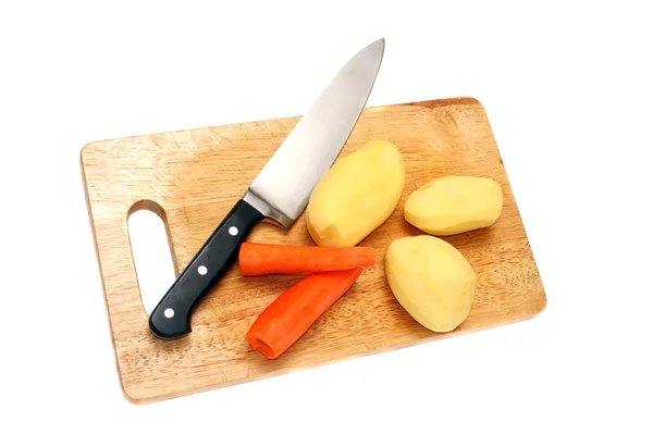Cuchillo, papa y zanahorias en una tabla de madera —  Fotos de Stock