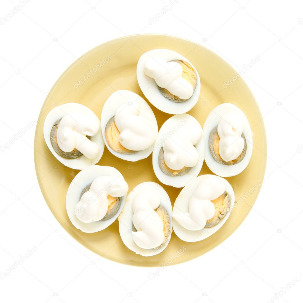 Eggs under mayonnaise on a yellow plate