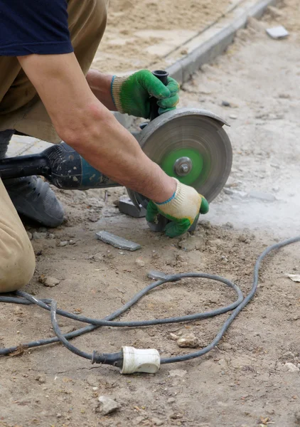 Arbetstagaren skär en sten den elektriska verktyget — Stockfoto