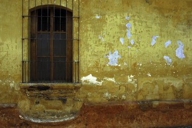 Barred window, yellow and red wall, Antigua, Guatemala. clipart