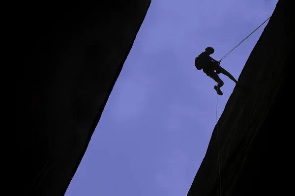 Kaya tırmanışçısı rappelling silüeti — Stok fotoğraf