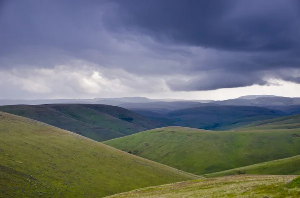 Green hills below storm clouds — Stock Photo, Image