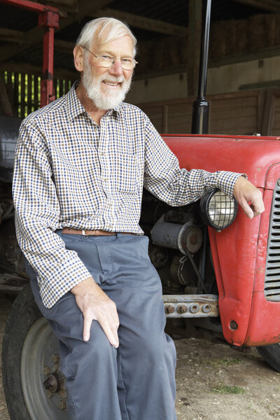 Organic Farmer Sitting Next To Old Fashioned Tractor