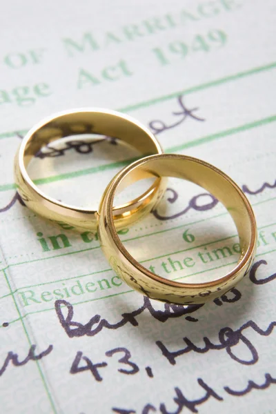 Anéis de casamento de ouro no certificado de casamento — Fotografia de Stock