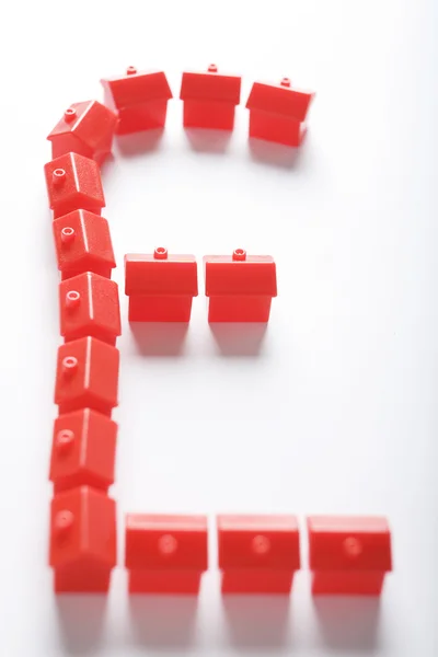 Rode miniatuur huizen in vorm van sterling symbool — Stockfoto