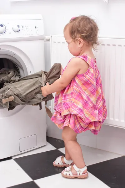 Ребенок тянется за стиральными вещами — стоковое фото